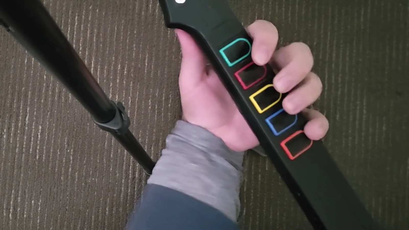 The Guitar Hero precedent Hand on a Guitar Hero controller neck with fingers on the colored fret buttons